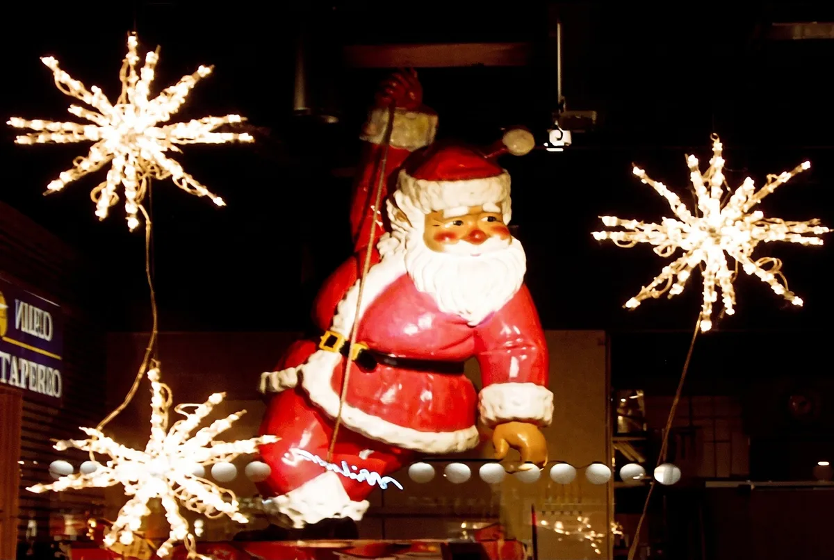 Santa figure and white starburst lights outside a storefront at night